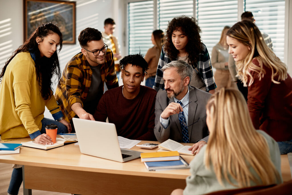 Mature teacher and group of his students using laptop at the university,
